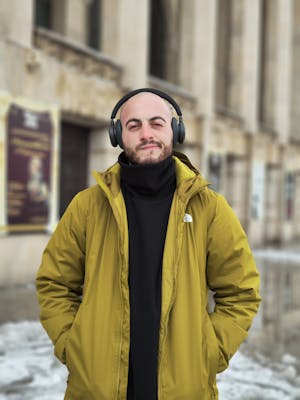 Bald Man with Headphones in Green Jacket