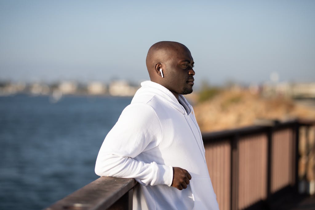 Man in White Hoodie Leaning on a Railing