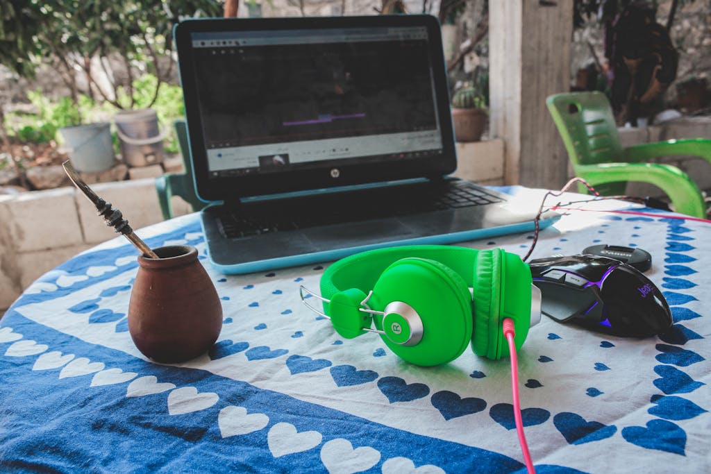 Green Corded Headphones Beside Blue and Black Laptop Computer